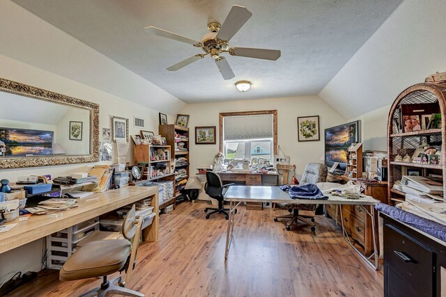 office area with a textured ceiling, ceiling fan, light wood-type flooring, and vaulted ceiling