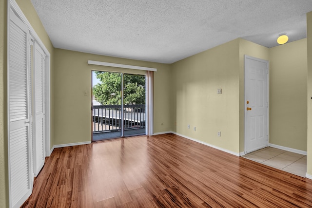 spare room with light wood-type flooring and a textured ceiling