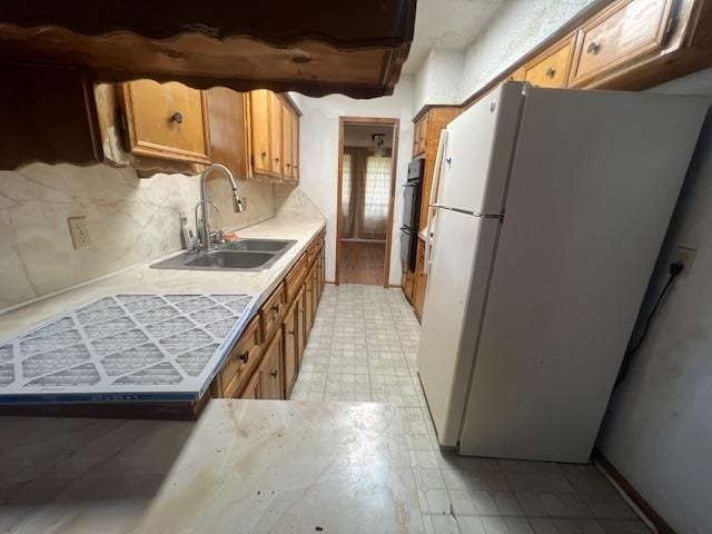 kitchen with black double oven, white refrigerator, tasteful backsplash, and sink