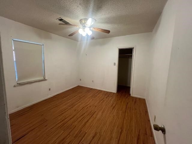 empty room with a textured ceiling, ceiling fan, and hardwood / wood-style floors