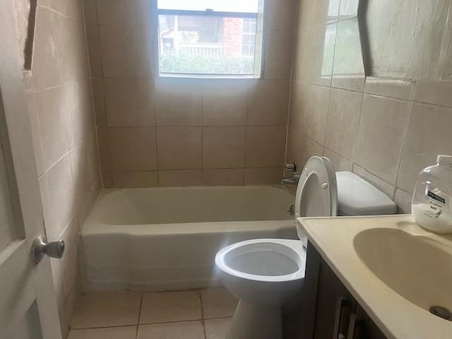 full bathroom featuring vanity, tile patterned flooring, tile walls, toilet, and tiled shower / bath