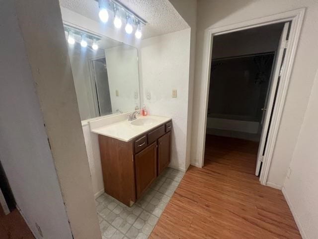 bathroom featuring vanity, a textured ceiling, wood-type flooring, and a shower