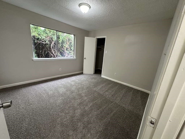 spare room with a textured ceiling and carpet floors