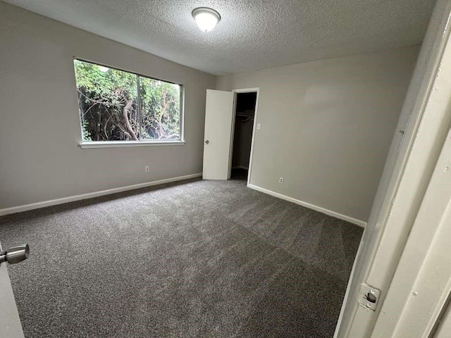 11807 S Youngwood Ln, Houston, TX 77043 - unfurnished bedroom with dark colored carpet, a textured ceiling, and baseboards