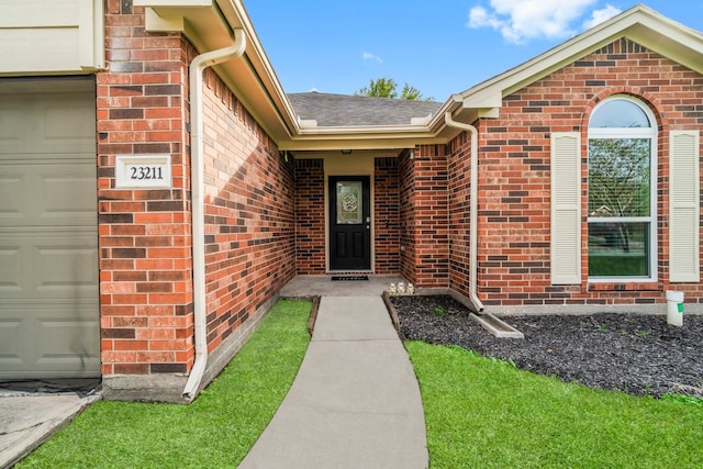 view of exterior entry featuring a yard and a garage