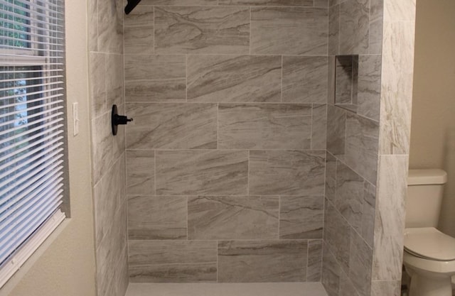 bathroom featuring toilet and a tile shower