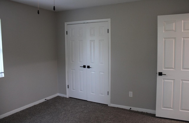 unfurnished bedroom featuring dark carpet and a closet