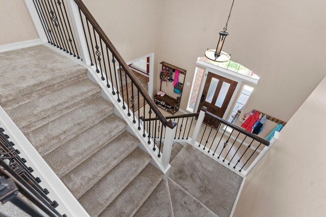 staircase featuring carpet flooring and a towering ceiling