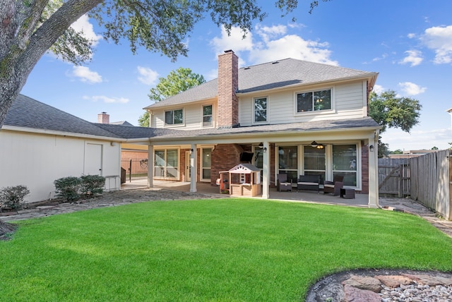 rear view of property with ceiling fan, a lawn, and a patio area