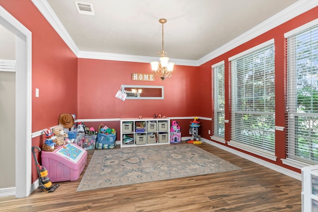 game room featuring ornamental molding, hardwood / wood-style floors, and an inviting chandelier