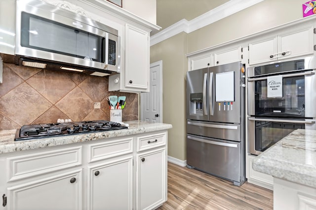 kitchen with backsplash, appliances with stainless steel finishes, light hardwood / wood-style floors, ornamental molding, and white cabinetry