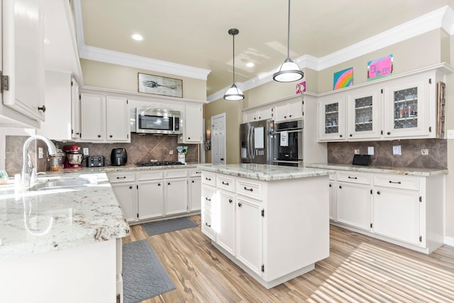 kitchen with a center island, decorative light fixtures, appliances with stainless steel finishes, and white cabinetry