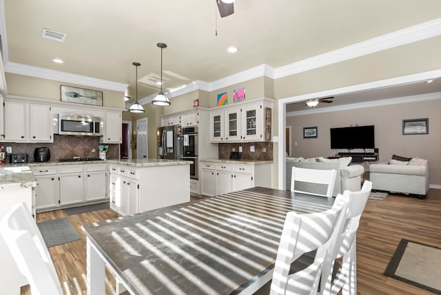 interior space featuring a kitchen island, ceiling fan, appliances with stainless steel finishes, and white cabinets