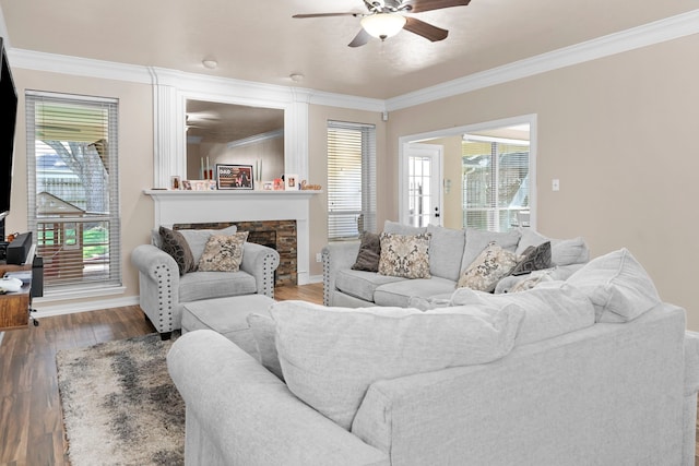 living room featuring dark wood-type flooring, ceiling fan, ornamental molding, and a fireplace