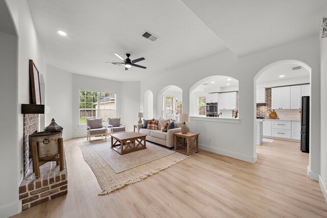 living room with light wood-type flooring, a fireplace, and ceiling fan