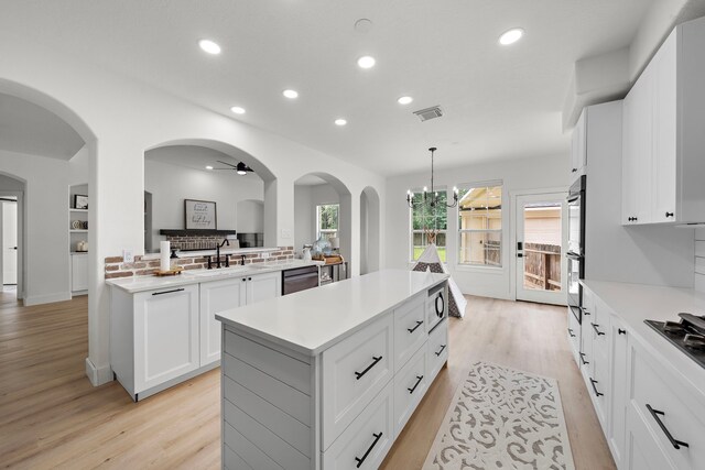 kitchen with pendant lighting, ceiling fan with notable chandelier, white cabinetry, a center island, and appliances with stainless steel finishes