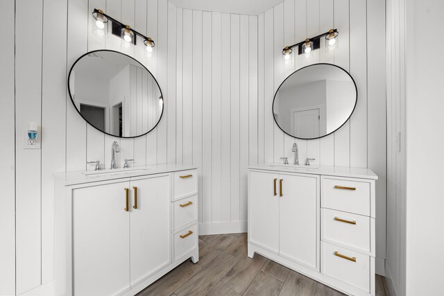 bathroom featuring hardwood / wood-style flooring, wooden walls, and vanity