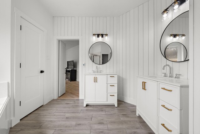 bathroom featuring vanity, wood walls, a bath, and wood-type flooring