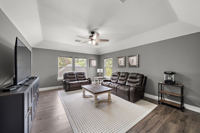 living room featuring ceiling fan, a tray ceiling, and dark hardwood / wood-style flooring