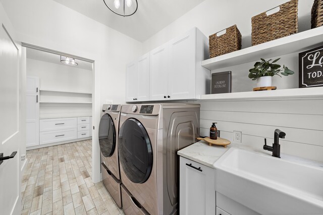 laundry area featuring washer and dryer, cabinets, and sink