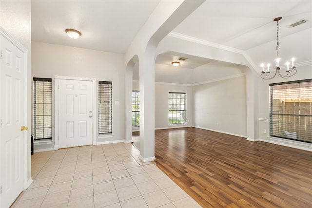 entryway featuring light wood-type flooring, ornamental molding, and a chandelier