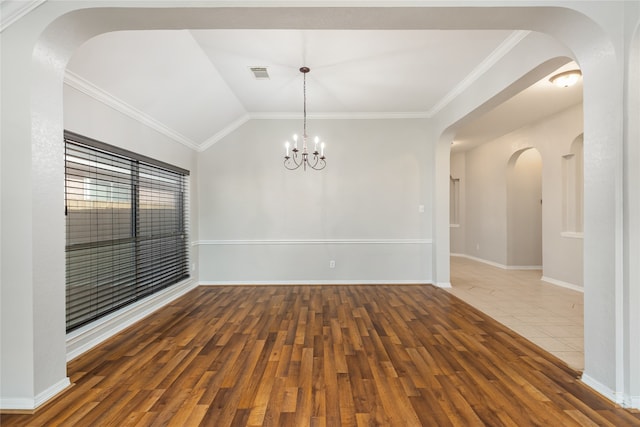 spare room featuring lofted ceiling, wood-type flooring, a notable chandelier, and ornamental molding