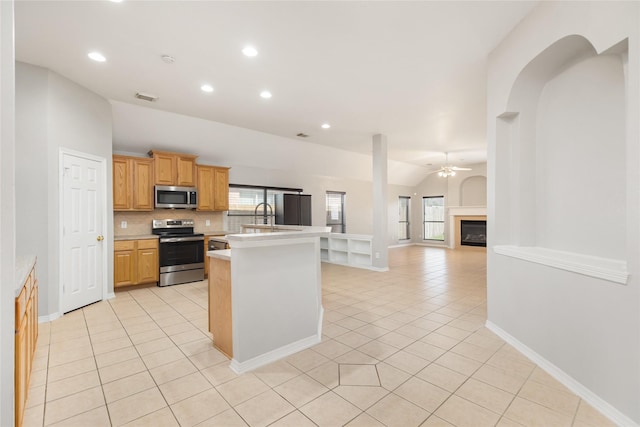 kitchen featuring light tile patterned floors, plenty of natural light, stainless steel appliances, and an island with sink