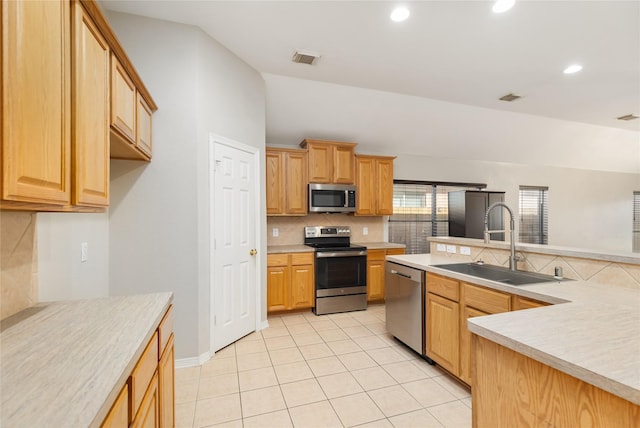 kitchen featuring sink, vaulted ceiling, light tile patterned floors, appliances with stainless steel finishes, and decorative backsplash