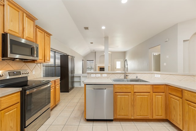 kitchen featuring light tile patterned floors, appliances with stainless steel finishes, sink, decorative backsplash, and lofted ceiling