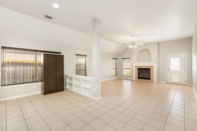 unfurnished living room with built in features, ceiling fan, light tile patterned floors, and vaulted ceiling