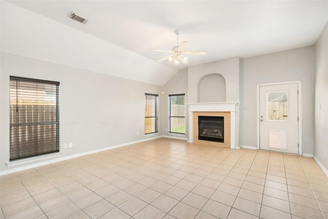 unfurnished living room featuring lofted ceiling, ceiling fan, a tiled fireplace, and light tile patterned floors