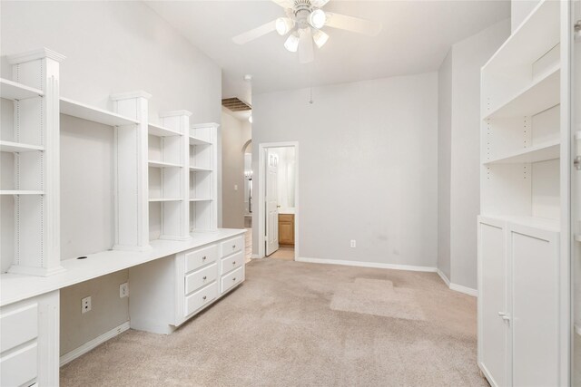 unfurnished office with light colored carpet, ceiling fan, and built in desk