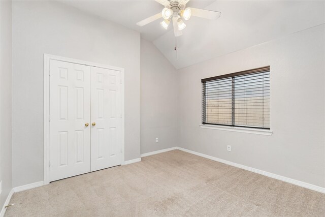 unfurnished bedroom featuring a closet, ceiling fan, light colored carpet, and vaulted ceiling