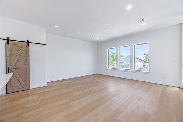 empty room featuring light hardwood / wood-style floors and a barn door