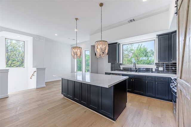 kitchen with backsplash, a barn door, a center island, an inviting chandelier, and light hardwood / wood-style floors