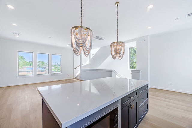 kitchen with a notable chandelier, light stone countertops, light hardwood / wood-style flooring, and decorative light fixtures