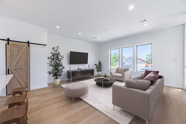 living room featuring light wood-type flooring and a barn door