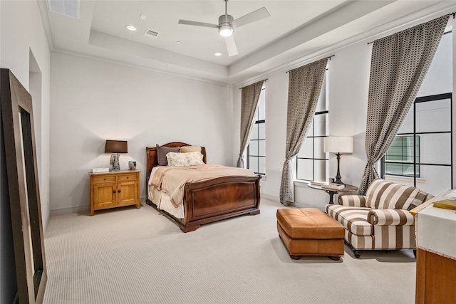 carpeted bedroom featuring ceiling fan, a tray ceiling, and multiple windows