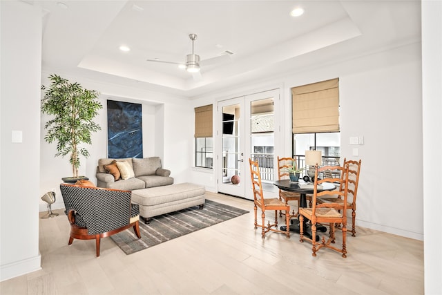 living room with a tray ceiling, french doors, ceiling fan, and light hardwood / wood-style floors