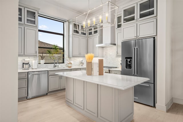 kitchen with a center island, stainless steel appliances, decorative light fixtures, and light hardwood / wood-style flooring