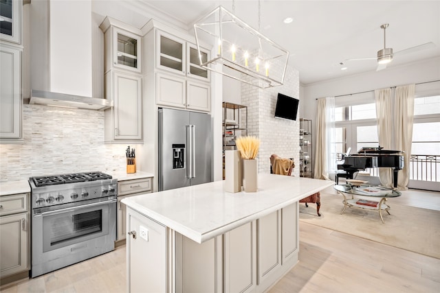 kitchen with a center island, light hardwood / wood-style flooring, wall chimney range hood, pendant lighting, and high quality appliances