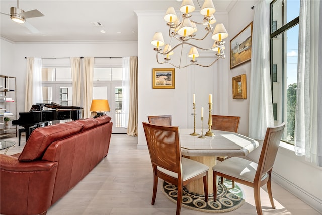 dining area featuring light wood-type flooring, ceiling fan with notable chandelier, and ornamental molding