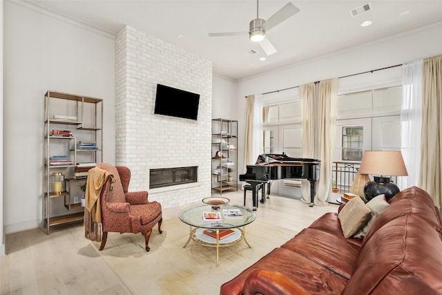 living room with a fireplace, light wood-type flooring, ornamental molding, and ceiling fan