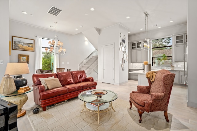 living room with ornamental molding, a chandelier, and light hardwood / wood-style floors