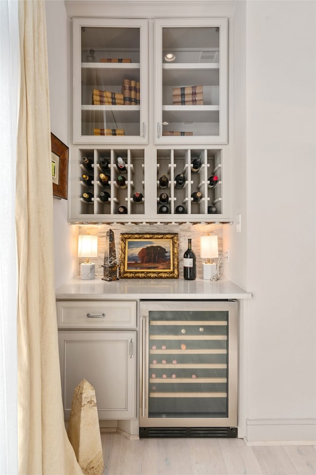 bar featuring tasteful backsplash, light hardwood / wood-style flooring, and wine cooler