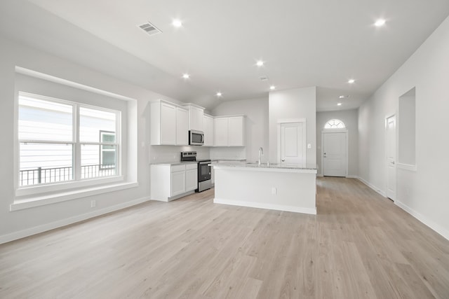 kitchen featuring an island with sink, white cabinets, light stone countertops, stainless steel appliances, and light hardwood / wood-style flooring