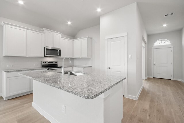 kitchen with appliances with stainless steel finishes, light hardwood / wood-style floors, white cabinetry, a center island with sink, and sink