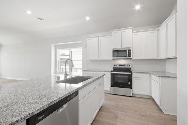 kitchen with light stone counters, sink, light hardwood / wood-style flooring, white cabinetry, and appliances with stainless steel finishes