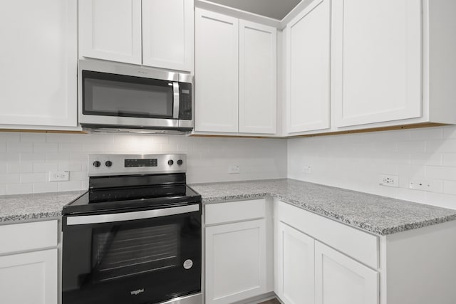 kitchen featuring light stone countertops, stainless steel appliances, white cabinets, and tasteful backsplash