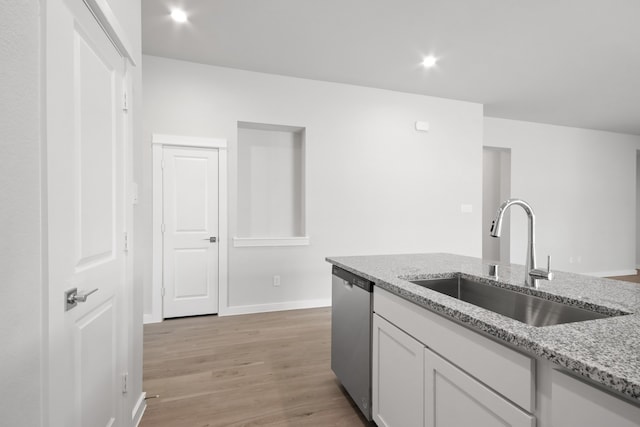 kitchen with white cabinets, sink, stainless steel dishwasher, light hardwood / wood-style flooring, and light stone countertops